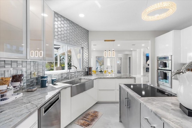 kitchen with tasteful backsplash, appliances with stainless steel finishes, white cabinetry, and a sink