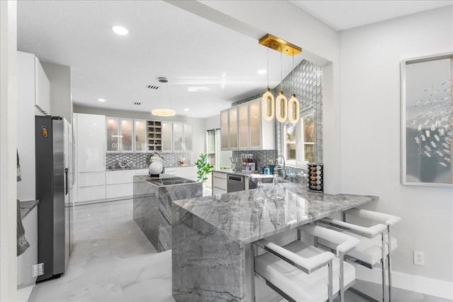 kitchen featuring backsplash, a peninsula, stainless steel appliances, and light stone countertops