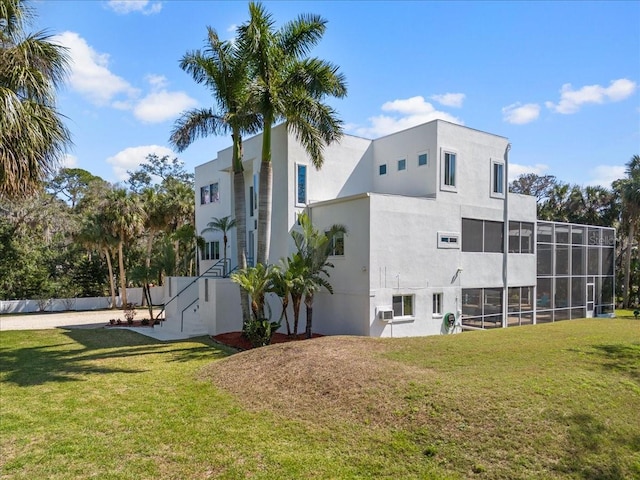 back of house with stucco siding and a yard