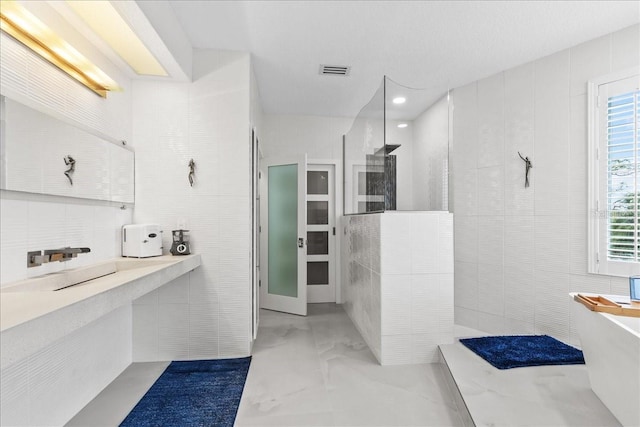 full bathroom with visible vents, plenty of natural light, a freestanding bath, and walk in shower