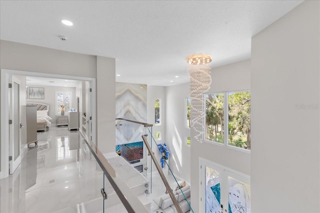 hallway with a notable chandelier, plenty of natural light, and recessed lighting