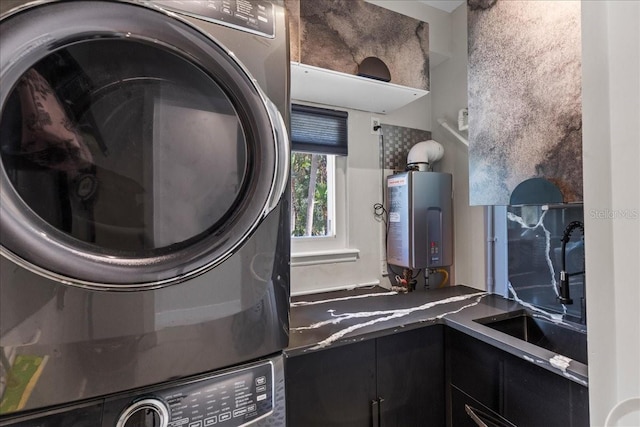 clothes washing area with tankless water heater, a sink, laundry area, and stacked washer / dryer