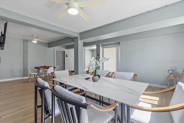 dining space featuring light wood finished floors, baseboards, and ceiling fan