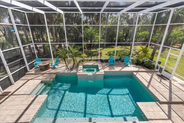 view of swimming pool featuring a patio, an outdoor fire pit, a pool with connected hot tub, and a lanai