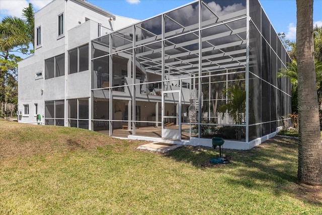 back of property featuring a lanai, stucco siding, and a yard