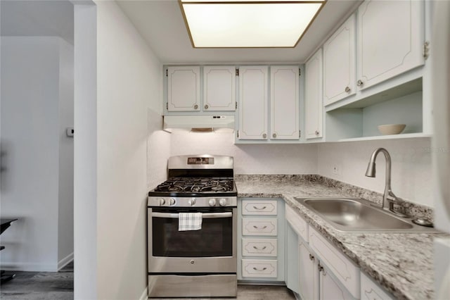 kitchen with light countertops, stainless steel gas stove, a sink, and under cabinet range hood