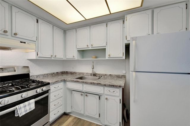 kitchen with light wood-style floors, freestanding refrigerator, a sink, gas range, and under cabinet range hood