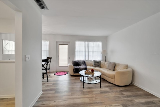 living area with visible vents, baseboards, and wood finished floors