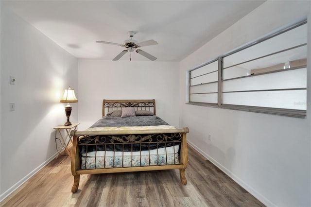 bedroom with a ceiling fan, baseboards, and wood finished floors