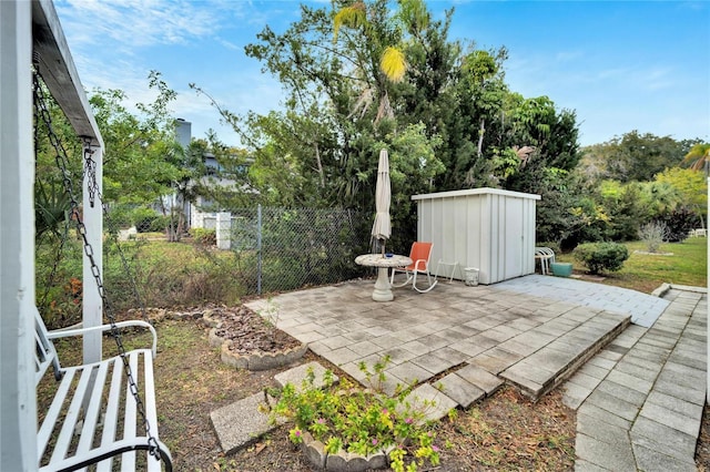 view of patio with a storage unit, fence, and an outdoor structure