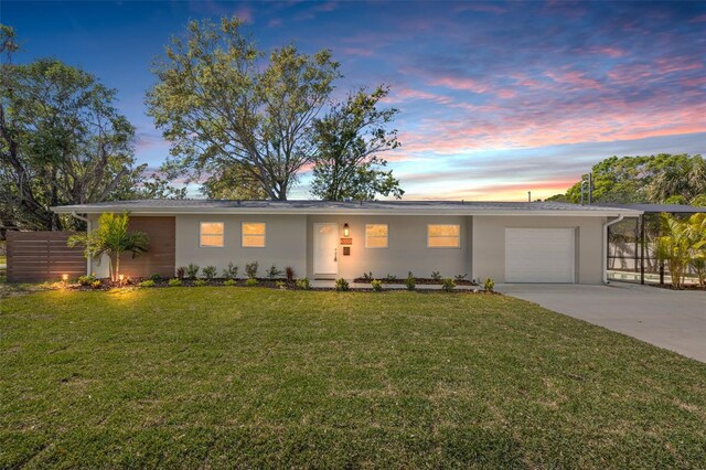 ranch-style home with a garage, driveway, fence, and a lawn