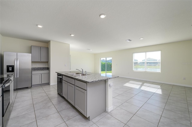 kitchen with stainless steel refrigerator with ice dispenser, gray cabinetry, a sink, light stone countertops, and dishwasher