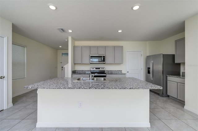 kitchen with a kitchen island with sink, gray cabinetry, stainless steel appliances, a sink, and visible vents