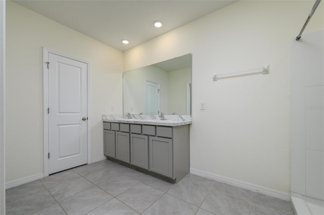 bathroom featuring double vanity, tile patterned floors, a sink, and baseboards