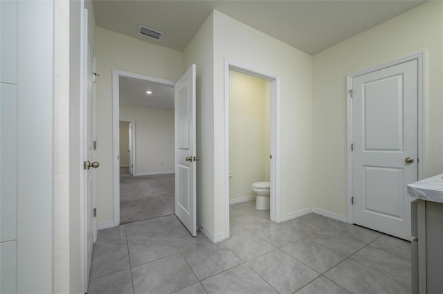 bathroom featuring baseboards, visible vents, toilet, and tile patterned floors