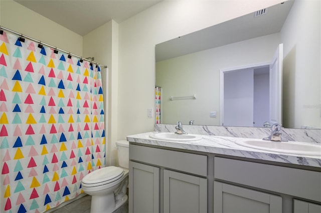 bathroom with toilet, double vanity, visible vents, and a sink