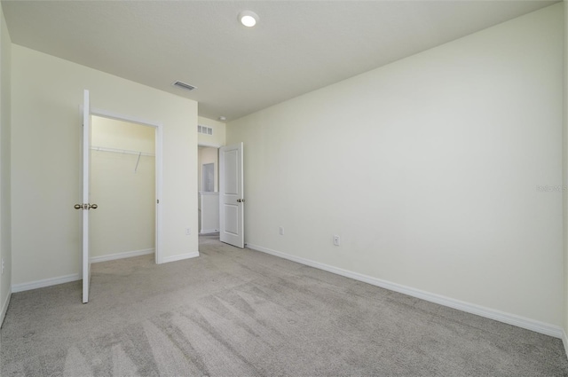 unfurnished bedroom with a closet, visible vents, light carpet, and baseboards