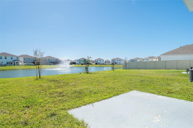 view of yard with a water view, a residential view, fence, and central AC