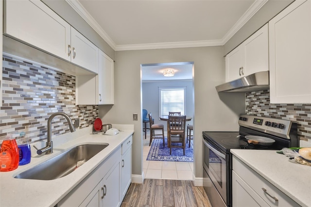 kitchen featuring crown molding, stainless steel electric stove, light countertops, a sink, and under cabinet range hood