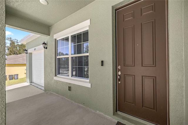 doorway to property featuring stucco siding and a garage