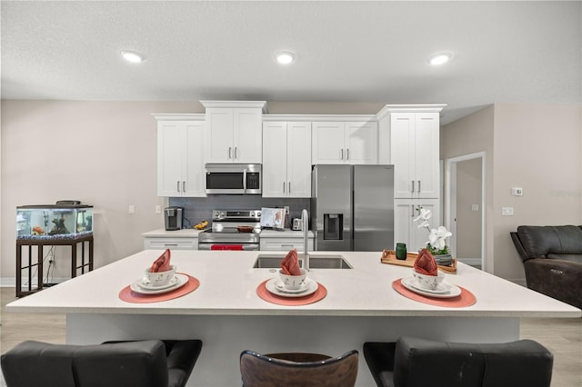 kitchen with white cabinetry, a breakfast bar area, appliances with stainless steel finishes, and a sink