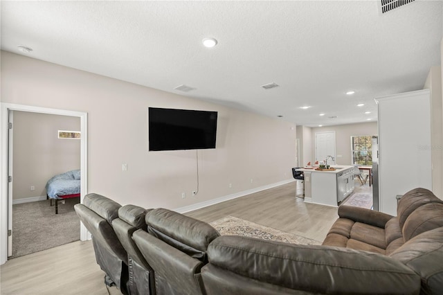 living area with light wood-type flooring, visible vents, and recessed lighting