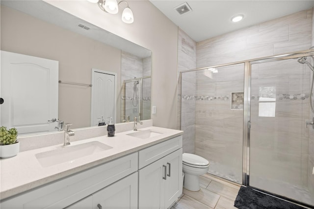 bathroom with a shower stall, double vanity, visible vents, and a sink