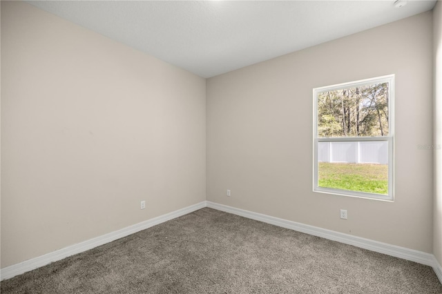 carpeted empty room featuring baseboards