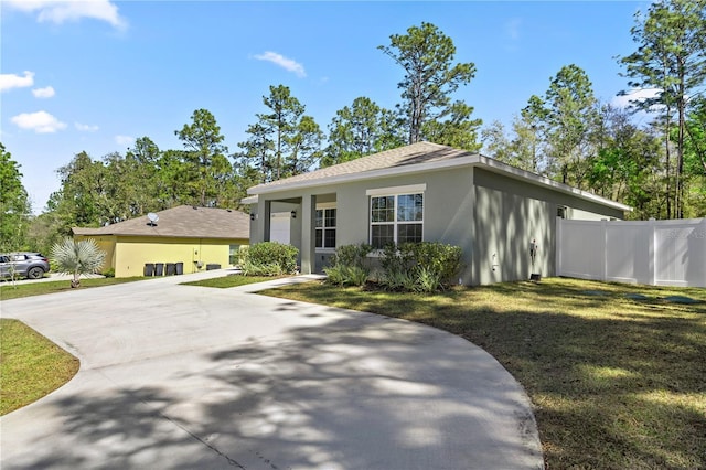 view of front of house with a front yard, fence, driveway, and stucco siding