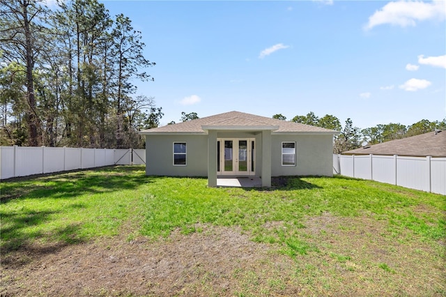 rear view of house with french doors, a yard, and stucco siding