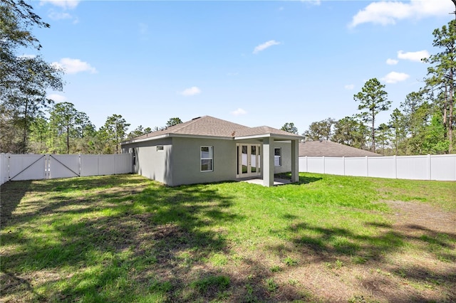 back of property featuring a yard, a fenced backyard, roof with shingles, and stucco siding