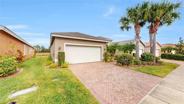 ranch-style home with a tile roof, an attached garage, decorative driveway, a front yard, and stucco siding