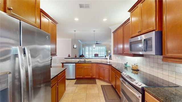 kitchen featuring visible vents, appliances with stainless steel finishes, backsplash, brown cabinets, and crown molding