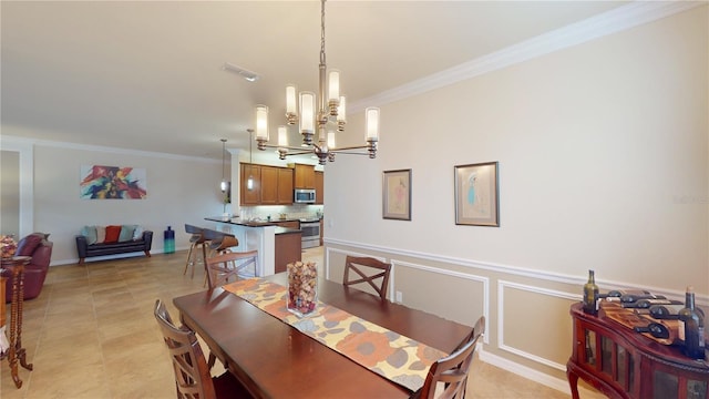 dining space featuring visible vents, a decorative wall, an inviting chandelier, ornamental molding, and wainscoting