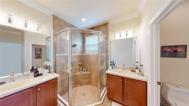 bathroom with toilet, two vanities, a sink, a stall shower, and crown molding