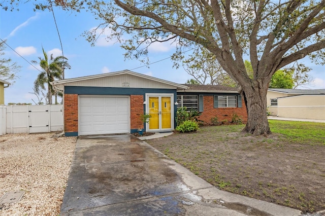 ranch-style house featuring brick siding, an attached garage, a gate, fence, and driveway