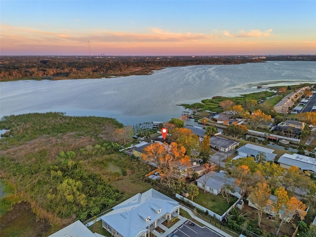 aerial view at dusk featuring a water view