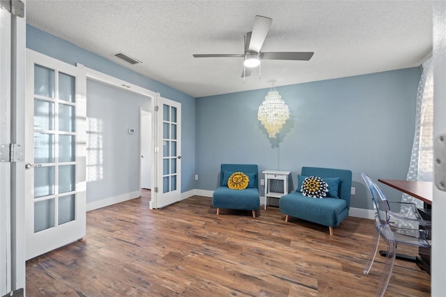 sitting room featuring french doors, visible vents, a textured ceiling, wood finished floors, and baseboards