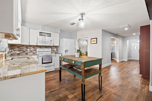 kitchen with white appliances, a sink, white cabinetry, decorative backsplash, and dark wood-style floors