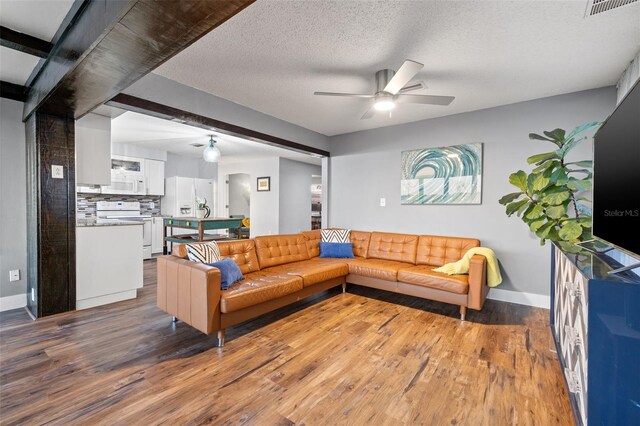 living room with a textured ceiling, visible vents, wood finished floors, and a ceiling fan