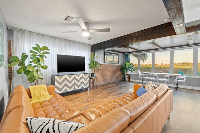 living room featuring visible vents, ceiling fan, a textured ceiling, brick wall, and wood finished floors