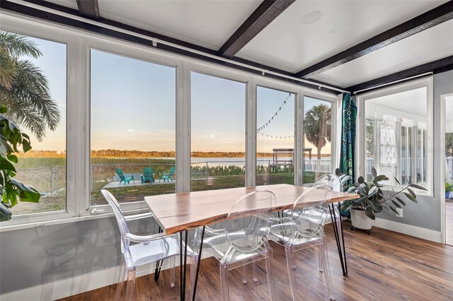 sunroom with beamed ceiling and a water view