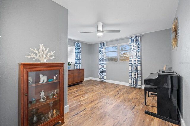 sitting room featuring a ceiling fan, baseboards, and wood finished floors