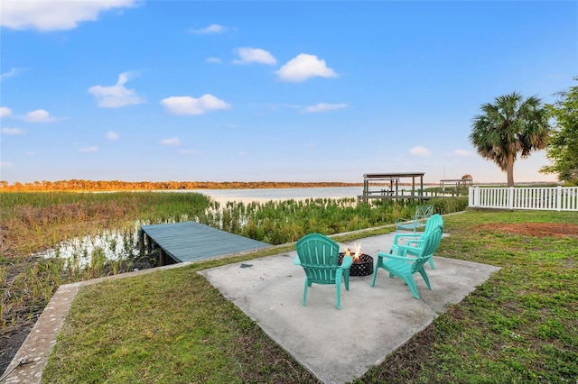 view of yard featuring a water view, a dock, fence, and a fire pit