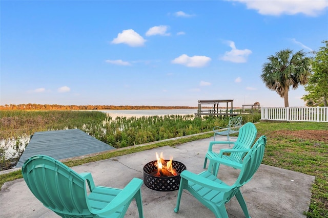 view of patio featuring an outdoor fire pit, a water view, and fence