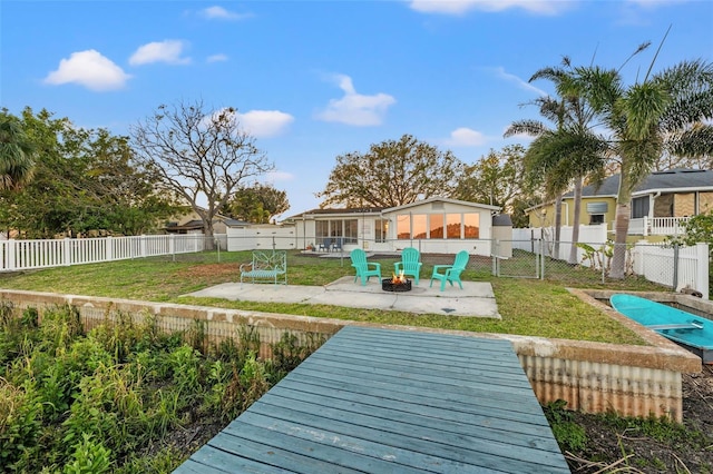 back of house featuring a patio area, an outdoor fire pit, a fenced backyard, and a yard