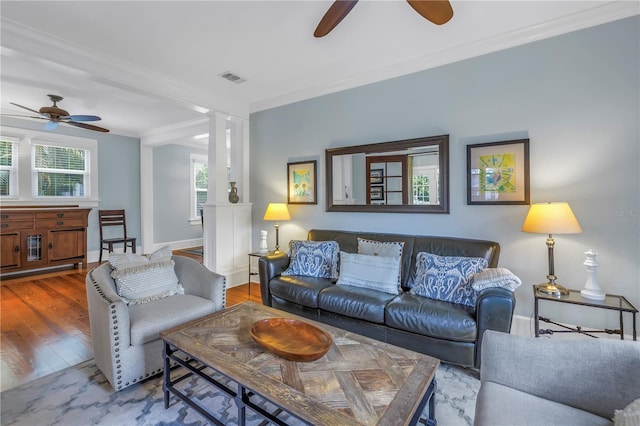 living room with baseboards, visible vents, a ceiling fan, ornamental molding, and wood finished floors