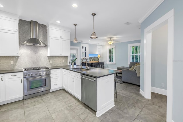 kitchen featuring dark countertops, wall chimney exhaust hood, appliances with stainless steel finishes, and a sink