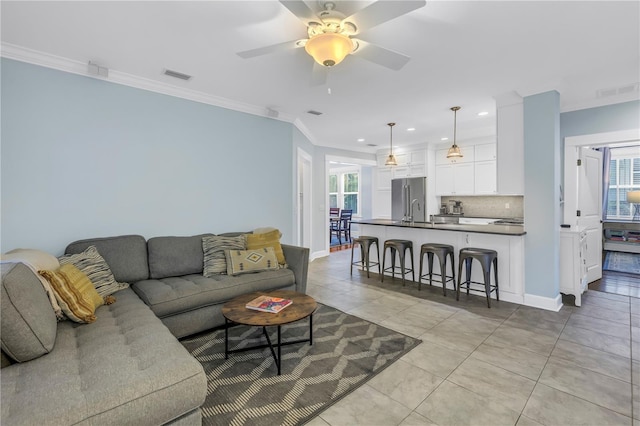 living area featuring ceiling fan, visible vents, crown molding, and light tile patterned floors