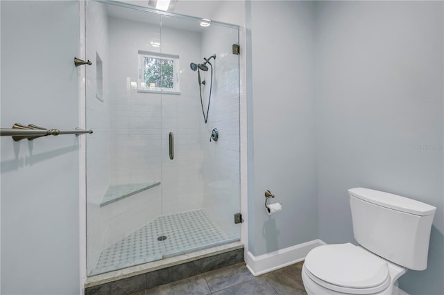 full bathroom with a stall shower, tile patterned flooring, toilet, and baseboards